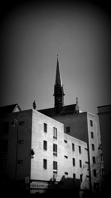 Statue by Anthony Gormley on the top of Blackwells Art and Poster shop, Broad Street, Oxford.